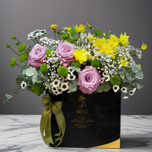 باکس گل مجلسی مشکی گلفروشی ارومیه شامل رزهای صورتی تازه، کرتنزیای سفید و زرد، برگهای سبز تزئینی و گلهای ریز ژپسوفیلا